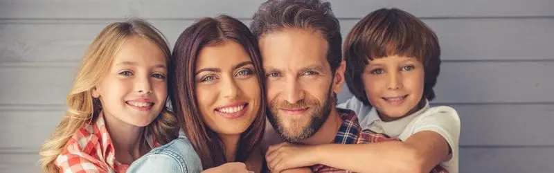 A man and woman smiling for the camera with two children.