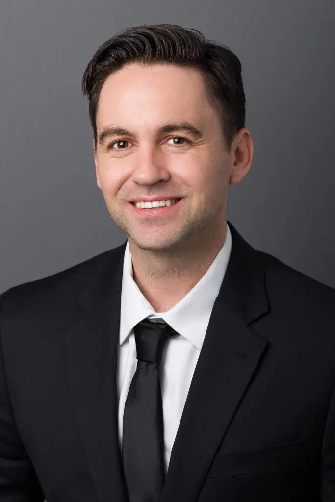 A man in a suit and tie smiling for the camera.