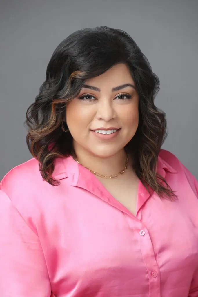 A woman in pink shirt smiling for the camera.