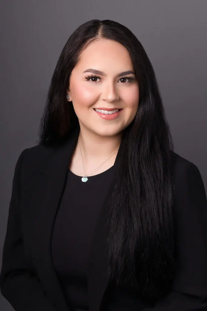 A woman in black jacket standing next to wall.