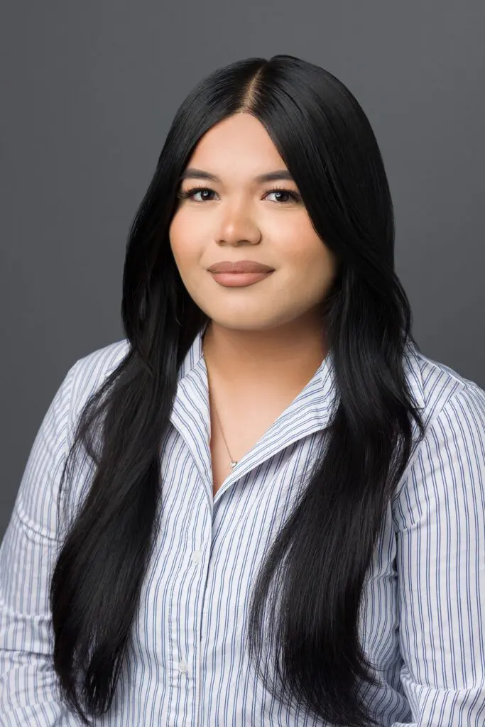 A woman with long black hair wearing a blue and white striped shirt.