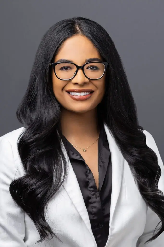 A woman with long black hair wearing glasses.