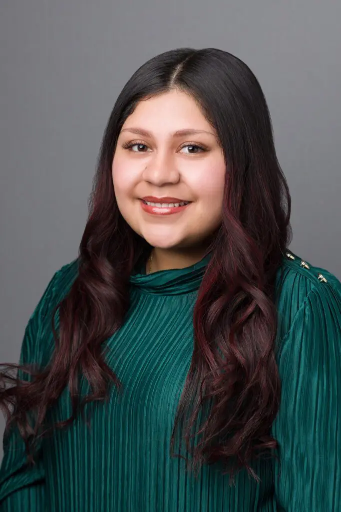 A young woman with long hair wearing green.