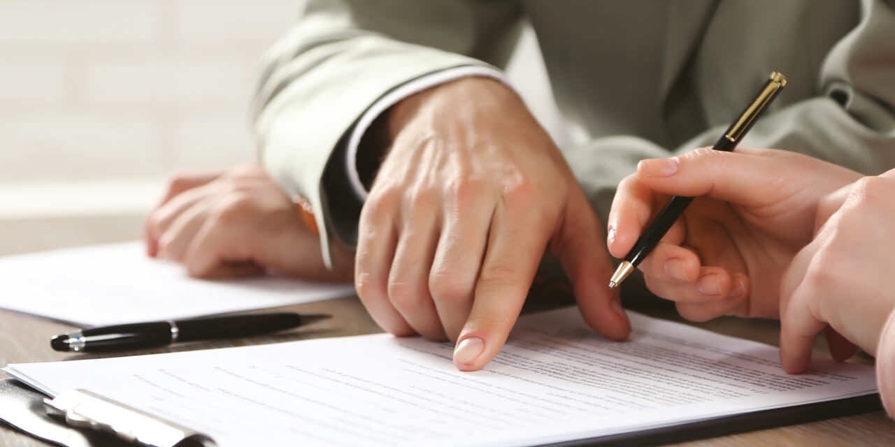 A person is writing on paper with a pen.