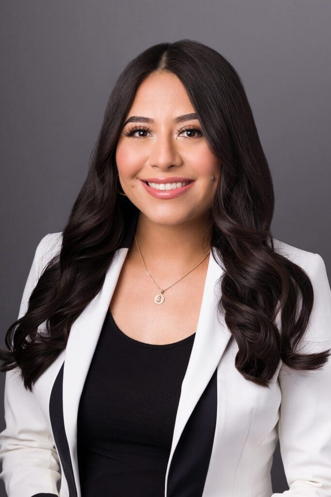 A woman in white jacket and black shirt smiling.