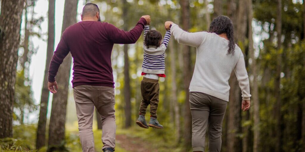 Family walking in forest, holding child’s hands. Family walking in forest, holding child's hands.