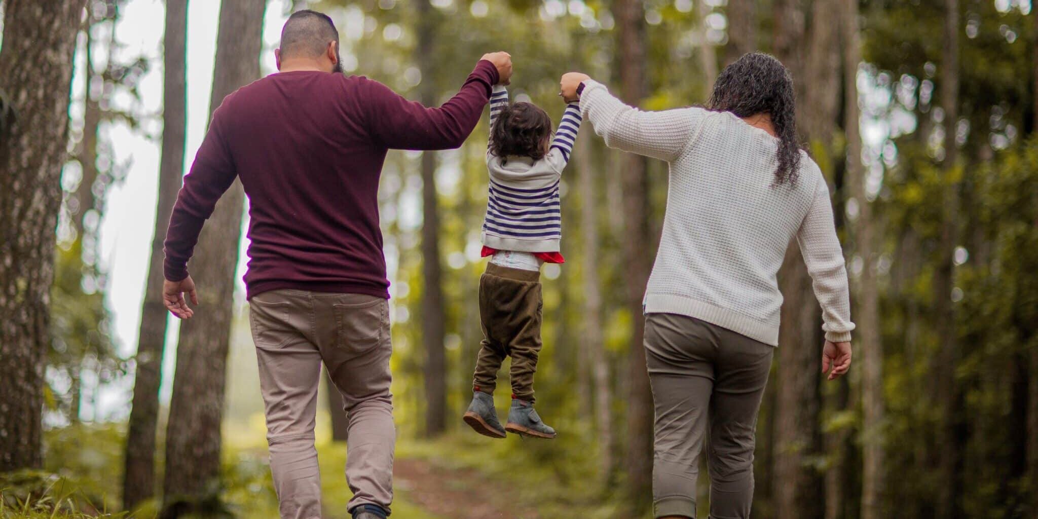 A man, woman and child walking through the woods.