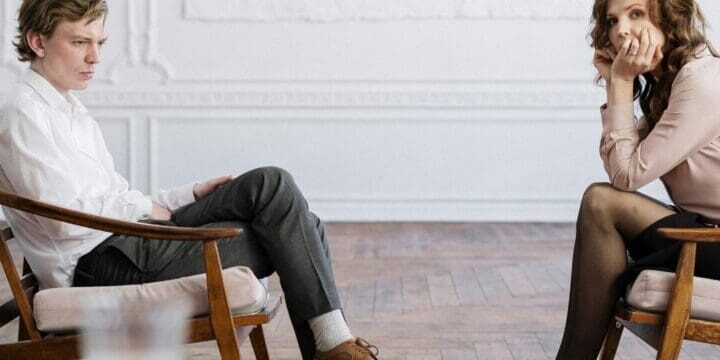 A man and woman sitting in chairs talking.