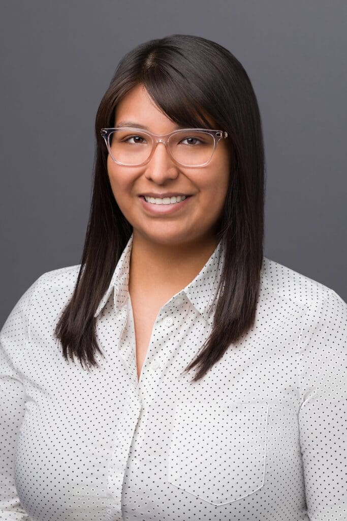 A woman with glasses and long hair wearing a white shirt.