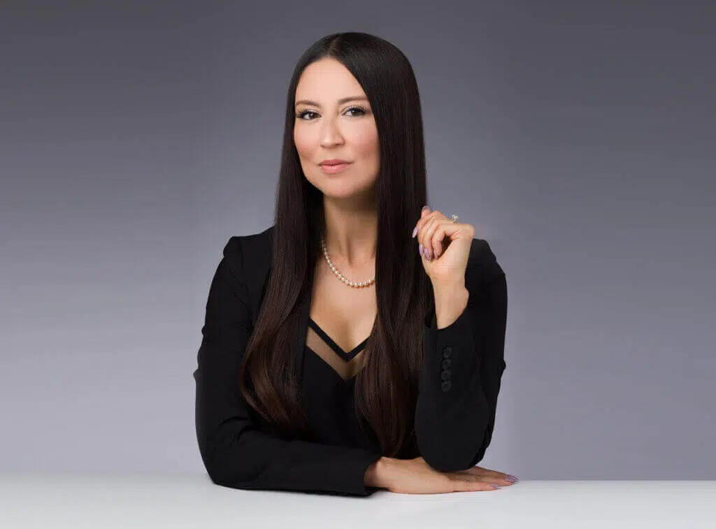 A woman sitting at a table with her hand on the shoulder of another person.