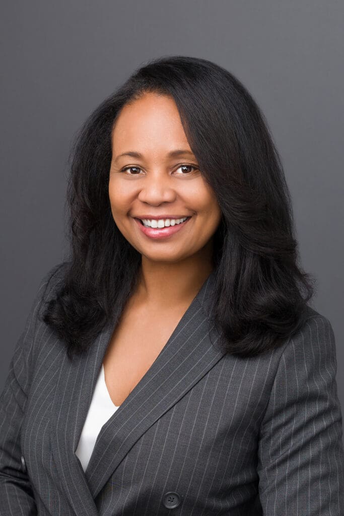 Smiling woman in a gray pinstripe suit.