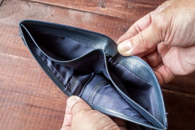 A person holding an empty wallet open on the table.