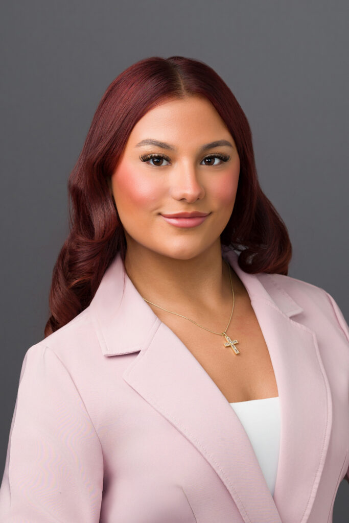 Professional portrait of a smiling woman in a light pink blazer.